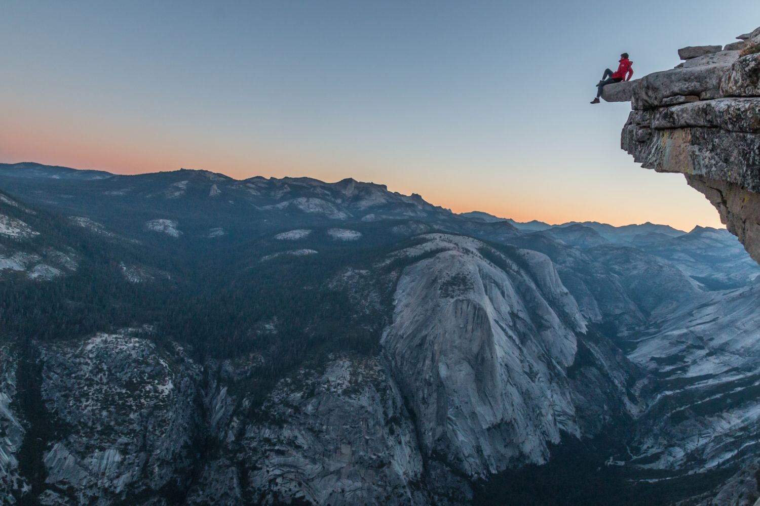 Eine Bergsteigerin ruht sich auf einer Klippe aus. Risikomanagement ist für sie privat und als Anlegerin ein Thema
